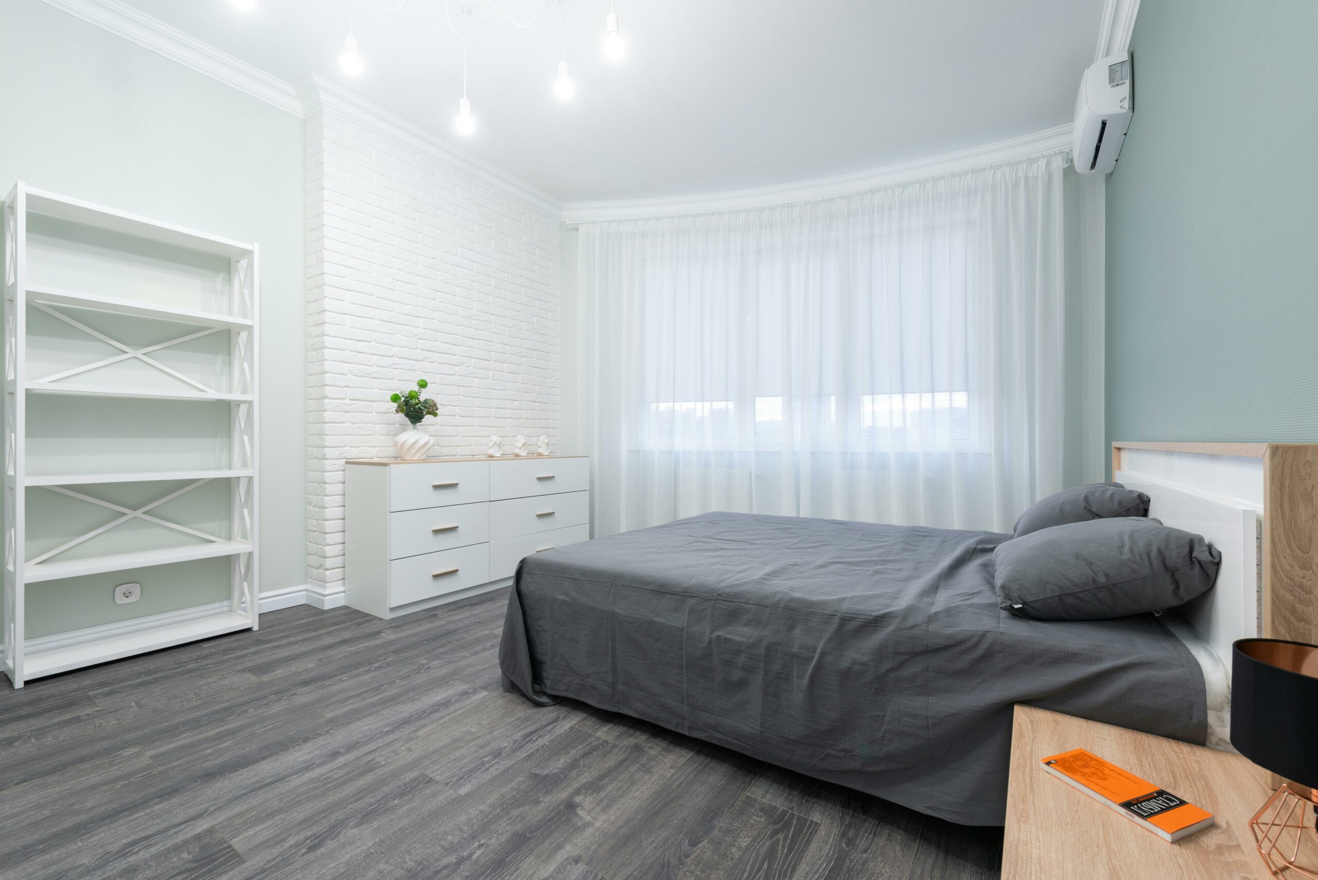 gray-bed-in-white-room-with-in-front-of-drawer-and-cabinets